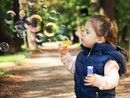 bambina che soffia nelle bolle di sapone