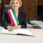 Donna sindaco con fascia tricolore che firma documenti