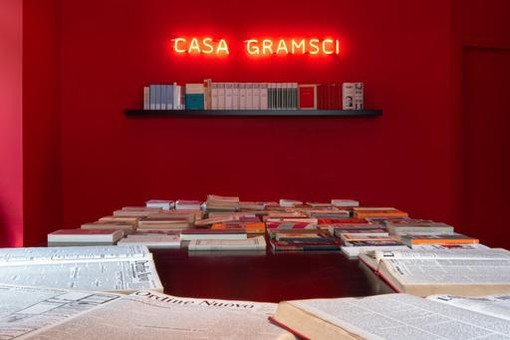 casa gramsci con scritta rossa luminosa e libri