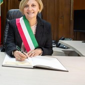 Donna sindaco con fascia tricolore che firma documenti