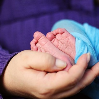 piedi di neonato nelle mani di un adulto