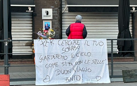 lenzuolo e fiori davanti a un bar con saracinesche abbassate