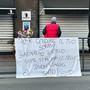 lenzuolo e fiori davanti a un bar con saracinesche abbassate