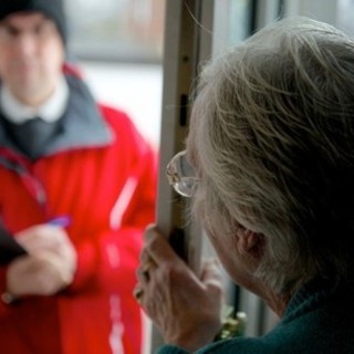 donna anziana apre la porta a uno sconosciuto vestito di rosso